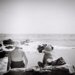 a couple of people sitting on top of a sandy beach