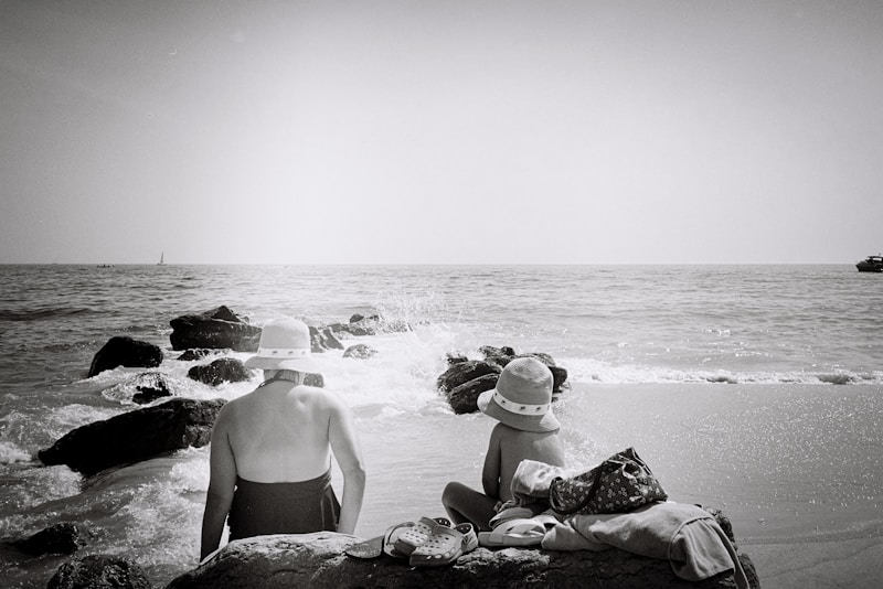 a couple of people sitting on top of a sandy beach
